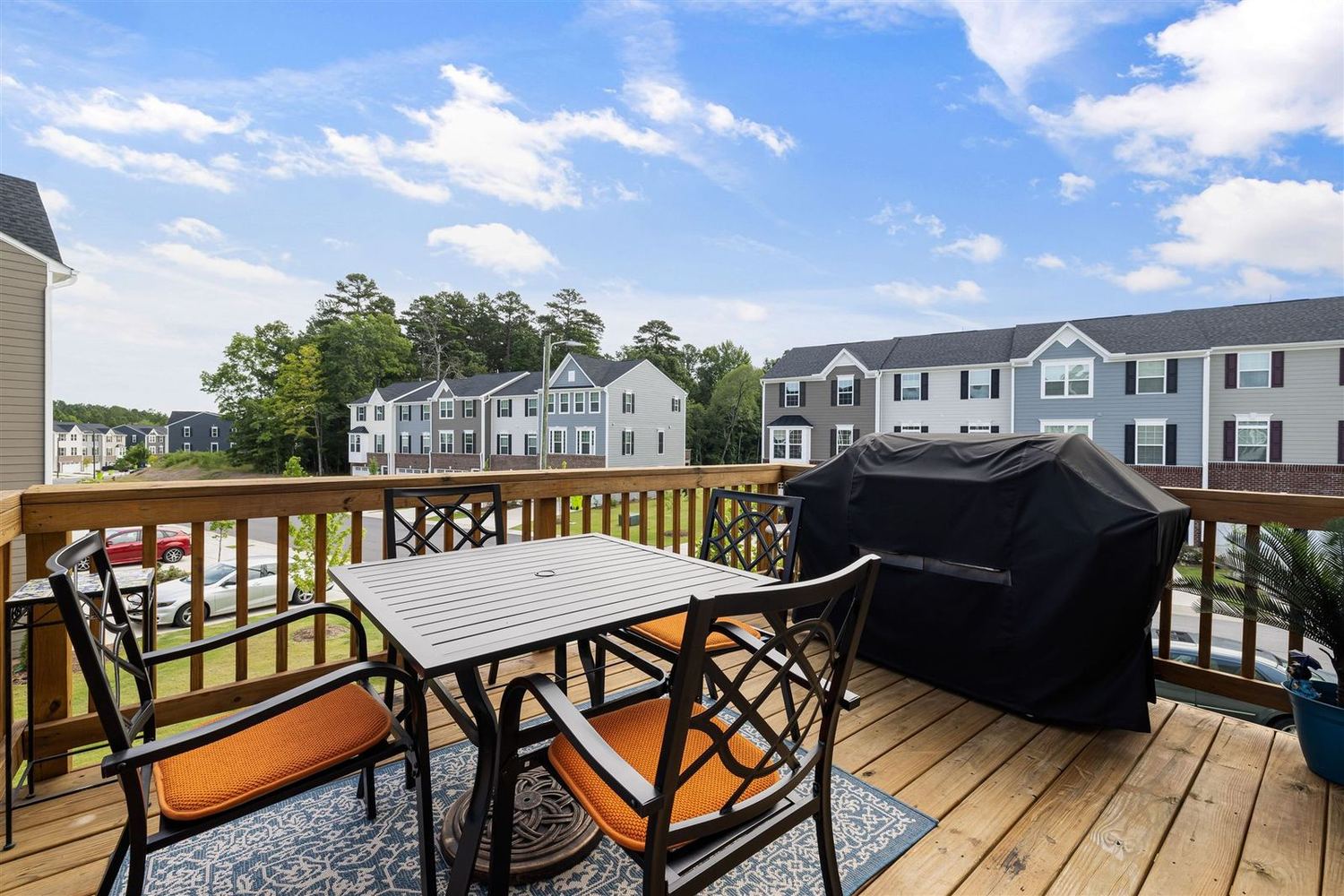 Elevated balcony deck with furniture overlooking townhomes