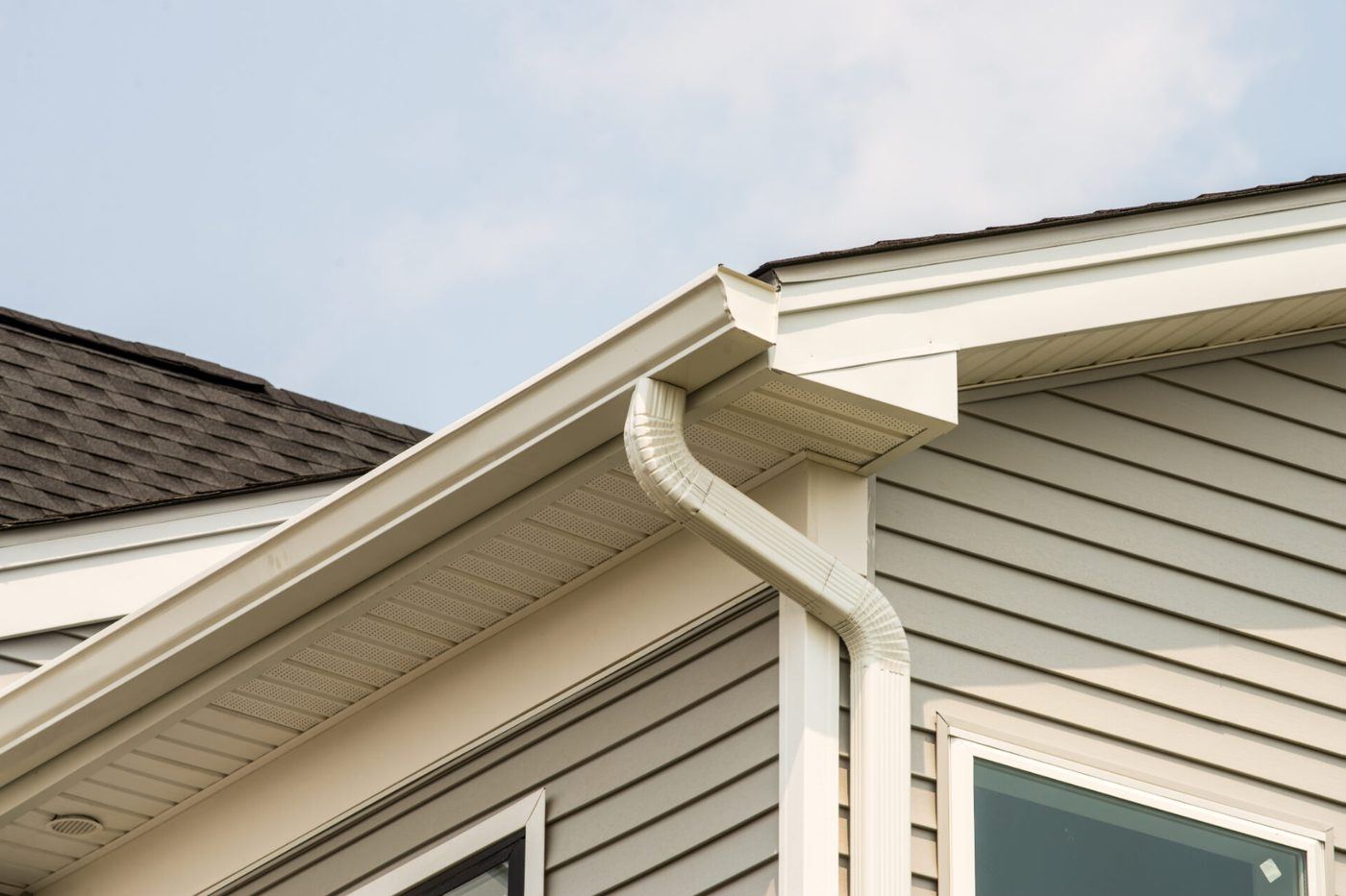 Gutter and downspout at the corner of a house, seen from below
