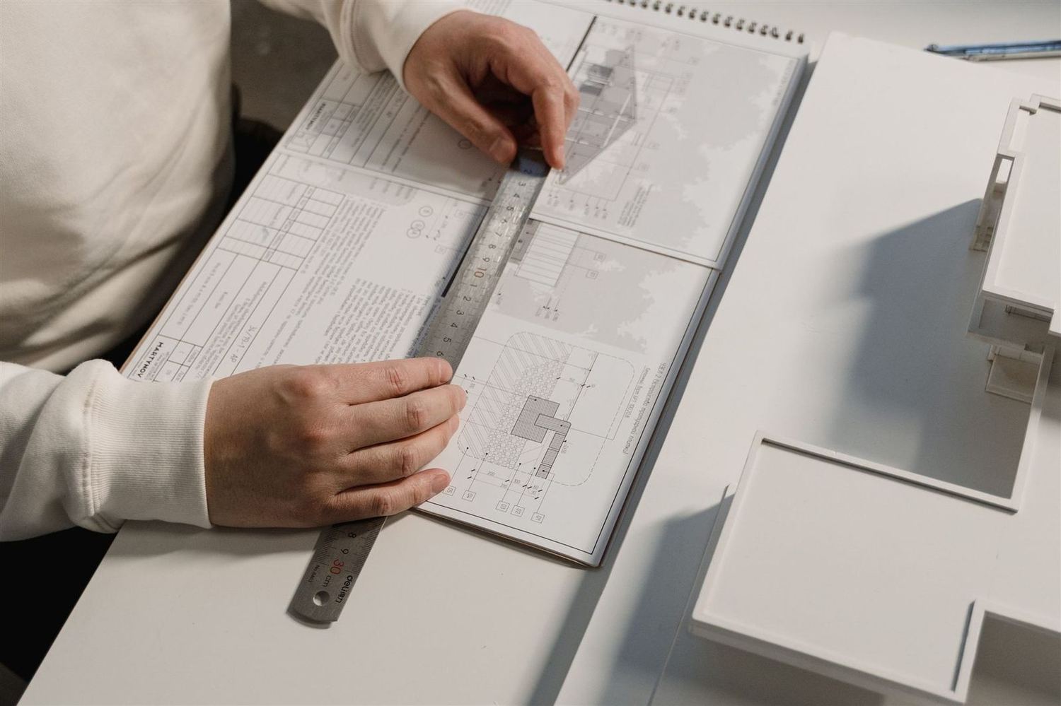 Hands measuring a set of drawings on a table